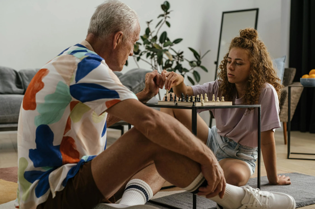 teen girl plays chess with her father