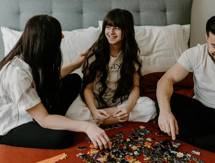 teen girl doing a puzzle with her parents