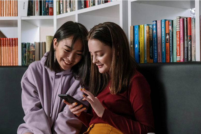 two teen girls looking at social media on a phone